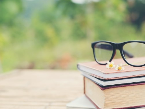 stack of books with pair of glasses on top